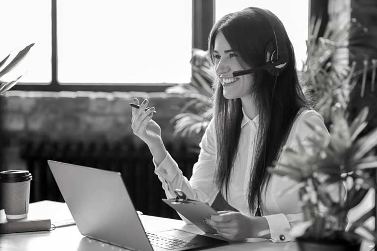 Photo noir & blanc, femme souriante avec casque audio au travail
